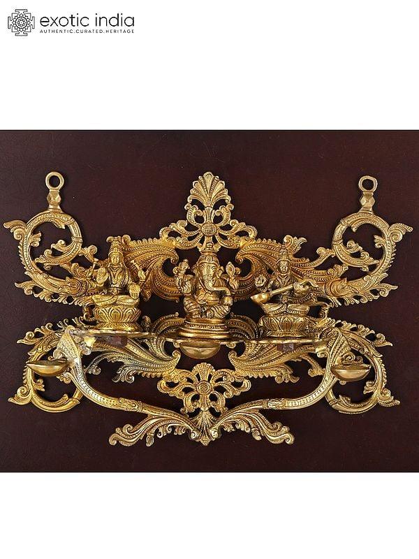 Exotic India 24" Lakshmi Ganesha Saraswati With Diya | Wood Framed Brass Sculpture | Wall Hanging 