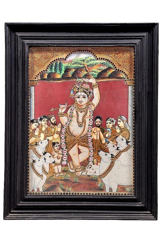 exotic india Lord Krishna Lifts Mount Govardhan Tanjore Painting | Traditional Colors With 24K Gold | Teakwood Frame | Gold & Wood | Handmade | Made In India