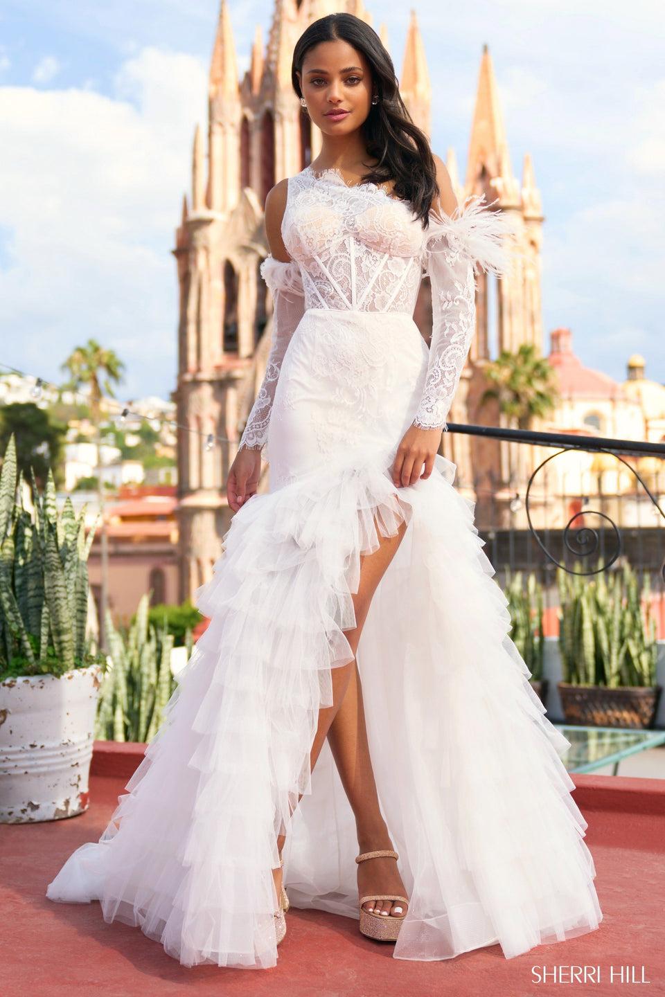 sherri hill One shoulder laced mermaid gown with a sheer corset bodice ruffled skirt with high slit and detachable sleeves with feathers